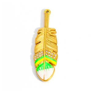 Macro view of gold-plated feather pendant with sparkling zircons and green enamel detail