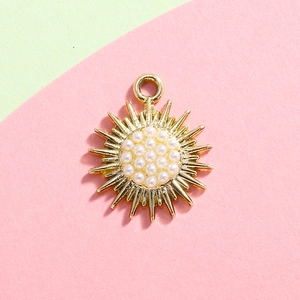 Detailed view of a gold sunburst pendant featuring white pearls on a split pastel background