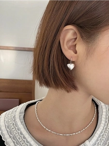 Detail shot of a silver heart earrings and necklace set on a model in soft lighting