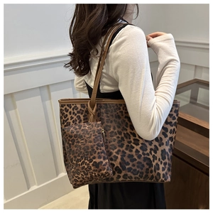 Close-up of leopard print tote bag and matching pouch held by a model in a warm interior