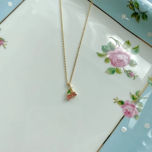 Detailed macro view of cherry pendant necklace with pink gemstones on floral plate