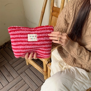 Detail of plush striped travel cosmetic bag with colorful pink and red fuzzy texture