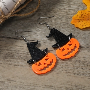 Halloween pumpkin head and black glitter witch hat earrings on a rustic wood background