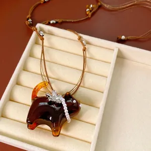 Handcrafted amber cat pendant necklace with pearl floral accents and brown woven cord