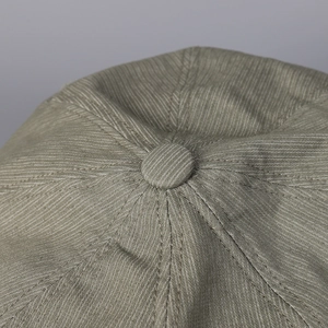 Macro shot of olive green vintage newsboy cap crown with detailed twill fabric stitching