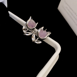 Macro shot of silver tulip stud earrings with purple crystals on a contrast background