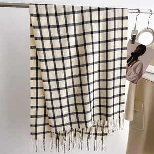 Detailed close-up of beige plaid scarf with black grid pattern and soft fringe tassels