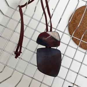 Detail view of irregular resin pendant with tortoiseshell pattern on brown rope cord