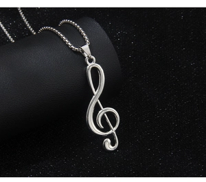 Macro shot of silver stainless steel treble clef musical note pendant on black background