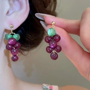 Detail of purple grape resin dangle earrings with green leaf beads and gold metal links