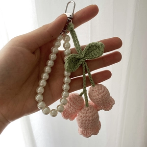Detail of pink lily of the valley crochet flowers and white pearl chain keychain