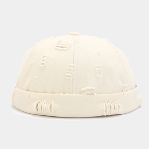 Detail of beige docker cap featuring distressed ripped holes and a rolled cuff design