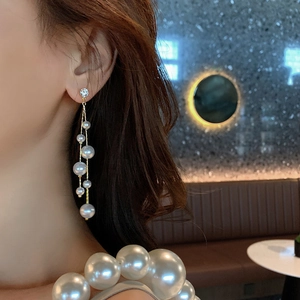 Detailed view of elegant long tassel earrings with white pearls and gold metal chain