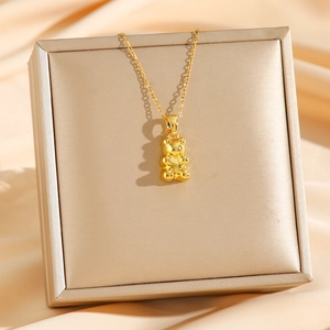 Polished gold teddy bear pendant necklace in minimalist style on luxury silk display