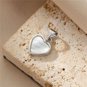Detailed close-up of heart-shaped silver pendant with white shell inlay on stone