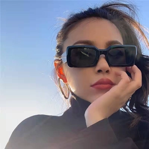 Modern black square frame sunglasses with dark lenses and oversized gold hoop earrings