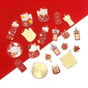 Dettaglio di ciondoli in lega rossa e oro con Maneki-neko e simboli della fortuna