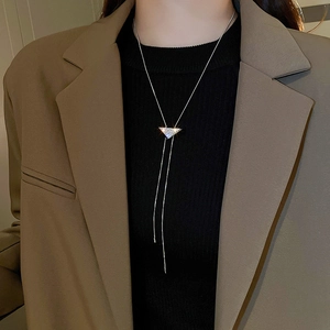 Macro detail of a silver-tone Y-shaped long necklace with a sparkling diamond triangle pendant
