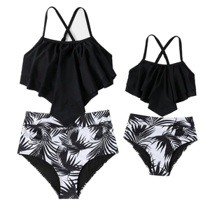 Matching black ruffle tankini set with tropical palm leaf print bottoms for mother and daughter