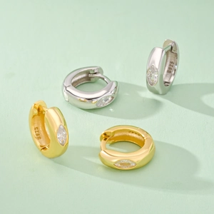 Detailed macro of S925 silver hoop earrings with marquise-cut cubic zirconia in gold and silver