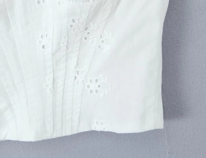 Détail du tissu en dentelle de coton blanc avec broderie florale et plis verticaux