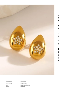 Détail de boucles d'oreilles goutte dorées avec zircon étoile sur socle minimaliste
