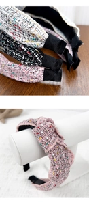 Close-up of knotted tweed headbands in pink, black, and beige with woven texture
