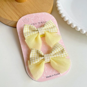 Détail des barrettes à cheveux à carreaux jaunes en coton et organza sur carte rose