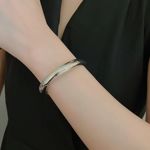 Polished silver cylindrical cuff bracelet with hinge detail on a model wrist