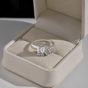 Macro detail of Toi et Moi silver ring with emerald and pear cut stones in a velvet box