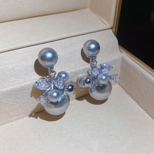 Détail de boucles d'oreilles élégantes en perles grises avec cristaux de zircon