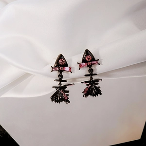 Close-up of pink zircon earrings with black metal frame on white silk background