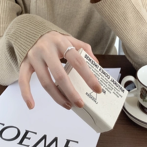 Close-up of irregular textured S925 sterling silver ring worn on index finger with zircon