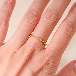 Macro close-up of a gold chain ring with sparkling diamonds on a finger