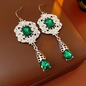 Detail of vintage palace style silver drop earrings with emerald green crystals