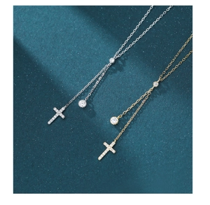 Detailed view of silver and gold cross necklaces with tassels on dark teal background