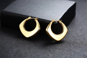 Detailed view of chunky hollow gold hoop earrings with a polished mirror finish on dark base