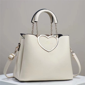 Close-up of a white tote bag featuring a gold heart-shaped buckle and lychee texture