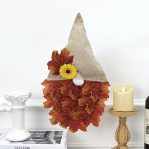 Detail of autumn gnome wall decor with burlap hat, sunflower, and red maple leaves