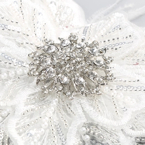 Vue détaillée de broderies florales à paillettes blanches avec perles et plumes