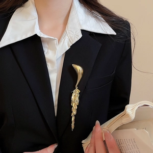 Detail of elegant gold fringe brooch with metal tassels worn on a black suit blazer lapel