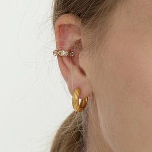 Close-up of gold-plated hoop earrings with vertical texture and marquise-cut gems