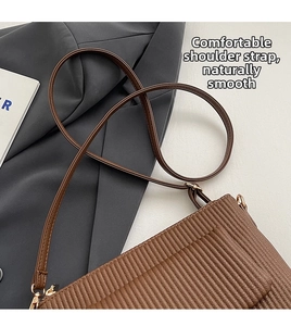 Detailed view of brown vertical pleated texture on a leather crossbody bag with strap