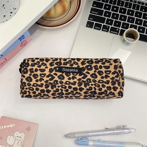 Flat lay of a leopard print canvas pencil case and stationery set on a white desk
