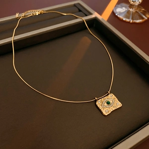 Dettaglio collana vintage a serpente con ciondolo occhio e pietra verde centrale
