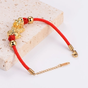 Detailed view of red braided bracelet with golden Pi Xiu charm and adjustable lobster clasp