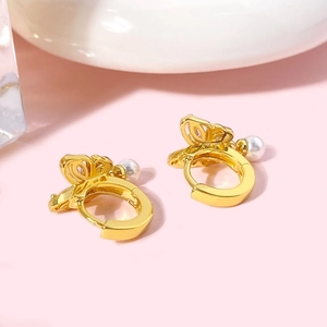 Détail macro de boucles d'oreilles papillon dorées avec perles et pierres de zircon
