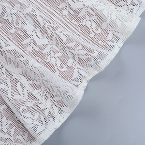 Gros plan sur le tissu en dentelle florale blanche et la texture de maille de la robe