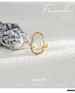 Detail of a gold irregular wave ring featuring a single white pearl on a stone surface