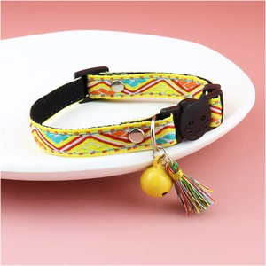 Detail of woven plaid cat collar featuring yellow bell, colorful tassel and cat-shaped buckle